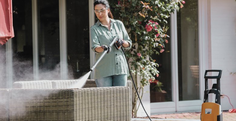 mujer limpiando los muebles de jardón con hidrolimpiadora